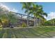 View of the screened-in patio with tropical landscaping and outdoor furniture, ideal for relaxation and entertaining at 7812 Birdie Bend Way, Sarasota, FL 34241