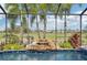 Pool area with screened enclosure, rock waterfall feature, lush landscaping, and golf course views at 7812 Birdie Bend Way, Sarasota, FL 34241