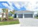 Charming single-Gathering home features a two-car garage, landscaped front yard with palm trees, and beautiful blue skies at 12440 Meribel St, Venice, FL 34293