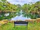 Relaxing pond view with fountain, lush trees reflecting on the water, and an inviting bench at 1407 Willow Oak Cir, Bradenton, FL 34209