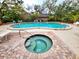 An in-ground pool with an attached spa is surrounded by a paver and concrete deck with trees at 1407 Willow Oak Cir, Bradenton, FL 34209