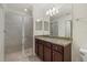 Bathroom featuring tiled walk-in shower, large mirror, and granite countertop vanity at 16904 Vardon Ter # 102, Bradenton, FL 34211