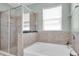 A luxurious bathroom features a separate shower and a soaking tub surrounded by stylish tile at 5718 Broad River Run, Ellenton, FL 34222