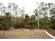 Spacious backyard featuring a gravel area and surrounding lush greenery and tall trees at 8570 Tropicaire Blvd, North Port, FL 34291