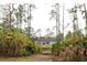 Back view of the property with a lush yard featuring a pond in the foreground and surrounded by tall trees and banana trees at 8570 Tropicaire Blvd, North Port, FL 34291