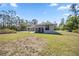 View of the house from backyard showcasing a covered patio, lawn, and natural landscaping at 8570 Tropicaire Blvd, North Port, FL 34291