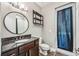 Bathroom featuring dark wood cabinets, a round mirror, and a walk-out door at 8570 Tropicaire Blvd, North Port, FL 34291