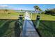 Exterior shot features a dock leading to the waterfront with lush grass landscaping and palm trees under a sunny, partly cloudy sky at 9464 St Marys Ct, Port Charlotte, FL 33981