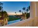 Expansive backyard featuring a pristine pool, manicured lawn, and lush palm trees at dusk overlooking the ocean at 1067 Westway Dr, Sarasota, FL 34236