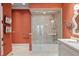 An orange-themed bathroom features a glass-enclosed shower-tub and patterned walls for a vibrant atmosphere at 1067 Westway Dr, Sarasota, FL 34236
