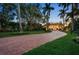 Elegant brick driveway leading to a luxurious home surrounded by lush greenery and palm trees at 1067 Westway Dr, Sarasota, FL 34236