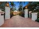 Grand gated entrance with brick driveway, lush landscaping, and stately pillars with lanterns at 1067 Westway Dr, Sarasota, FL 34236