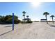 A beach volleyball net and picnic tables, set against a backdrop of swaying palm trees and sunny skies at 2020 Harbourside Dr # 432, Longboat Key, FL 34228