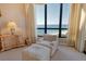 Bedroom with stunning ocean view from the large windows and an comfortable chair with ottoman at 435 L Ambiance Dr # L807, Longboat Key, FL 34228