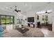 Bright living room featuring a ceiling fan, tile flooring, and natural light from the large windows at 8079 36Th Street E Cir, Sarasota, FL 34243