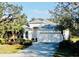 Home featuring mature landscaping, an attached two-car garage, and a charming white exterior at 8134 Coates Row Pl, Bradenton, FL 34201
