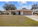 Charming single-story home with a well-maintained lawn, attached garage, and mature trees at 1058 Bounds St, Port Charlotte, FL 33952