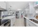 Modern kitchen with stainless steel appliances, white cabinets, a spacious island, and a view into the living area at 120 Maple Ave, Anna Maria, FL 34216