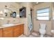 Bathroom featuring a sink, vanity, toilet, and a tiled shower with a window at 1206 2Nd E Ave, Bradenton, FL 34208