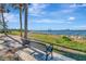 Scenic waterfront view with a bench, palm trees, and a pier extending into the sparkling water at 1206 2Nd E Ave, Bradenton, FL 34208