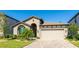 Charming single-story home featuring manicured landscaping, a blue sky, and an attached two-car garage at 12750 Oak Hill Way, Parrish, FL 34219