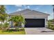 Charming home featuring a well-manicured lawn, paved driveway and a black garage door surrounded by beautiful landscaping at 26936 Lark Ct, Punta Gorda, FL 33955