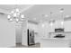 Open floorplan of kitchen featuring a chandelier, pendant lights, white cabinets, stainless appliances, and island at 26936 Lark Ct, Punta Gorda, FL 33955