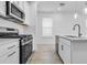 Bright kitchen featuring white cabinets, stainless steel appliances, and a large island with a sink and modern faucet at 26936 Lark Ct, Punta Gorda, FL 33955