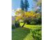 Beautiful home exterior featuring green lawn, a flowering tree and lush landscaping under a sunny blue sky at 3417 Tallywood Ln, Sarasota, FL 34237