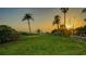 Sprawling backyard with lush green grass, palm trees, and a serene view of the beach at sunset at 4473 Gulf Of Mexico Dr, Longboat Key, FL 34228