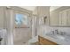 Bright bathroom featuring a walk-in shower, window, and a marble-topped wooden vanity with chrome fixtures at 4473 Gulf Of Mexico Dr, Longboat Key, FL 34228