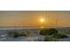 Golden sunset over the ocean, framed by beach grass, creating a serene and inviting coastal setting at 4473 Gulf Of Mexico Dr, Longboat Key, FL 34228