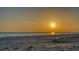 Tranquil beach scene at sunset with golden light reflecting on the calm ocean waters and sandy shore at 4473 Gulf Of Mexico Dr, Longboat Key, FL 34228