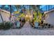Elegant gated entrance framed by tropical landscaping, with a brick path leading to the main entrance of the home at 4473 Gulf Of Mexico Dr, Longboat Key, FL 34228