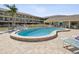 Community outdoor pool with lounge chairs and a nearby building at 460 S Paula Dr # 304, Dunedin, FL 34698