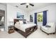 Well-lit bedroom featuring a ceiling fan, a dark wood bed frame, and a white armchair at 4721 Mainsail Drive, Bradenton, FL 34208