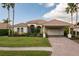 Inviting single-story home with a tile roof, lush landscaping, and covered carport entrance at 4721 Mainsail Drive, Bradenton, FL 34208