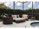 Relaxing screened patio with cushioned wicker furniture, decorative pillows, and view of lush greenery, near to a hot tub at 4721 Mainsail Drive, Bradenton, FL 34208
