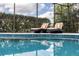 Tranquil swimming pool with clear, blue water, deck chairs, and a screened enclosure for a serene outdoor experience at 4721 Mainsail Drive, Bradenton, FL 34208