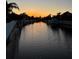 Picturesque waterfront view at sunset, featuring a tranquil canal and charming boat dock at 4721 Mainsail Drive, Bradenton, FL 34208