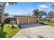 Home exterior showcasing a well-maintained lawn, mature trees, and a two-car garage at 6650 Schooner Bay Cir # 6650, Sarasota, FL 34231