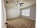 Bright bedroom featuring neutral carpeting, a ceiling fan, and a large window offering ample natural light at 6768 Breezy Palm Dr, Riverview, FL 33578