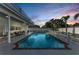 Beautiful pool area with a large pool, white fence, seating, and colorful sunset in the background at 7912 Desoto Memorial Hwy, Bradenton, FL 34209