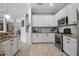Well-equipped kitchen with white cabinets, stainless steel appliances, granite countertops, and light-colored wood flooring at 13303 Swiftwater Way, Lakewood Ranch, FL 34211