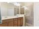 Well-lit bathroom featuring dual sinks with vanity, a glass-enclosed shower, and tile floors at 20170 Benissimo Dr, Venice, FL 34293