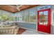 Cozy screened porch with comfortable seating, wood ceiling, and natural light from large windows at 310 S Osprey Ave, Sarasota, FL 34236