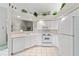Bright kitchen with white cabinets, a pass-through to the dining room and pristine white tile flooring at 4528 Fern Dr, Bradenton, FL 34208