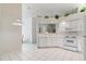 Clean kitchen with a window pass-through, white cabinets, white appliances and white tile flooring at 4528 Fern Dr, Bradenton, FL 34208