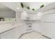 Bright white kitchen with a window pass-through, white cabinets, white appliances and white tile flooring at 4528 Fern Dr, Bradenton, FL 34208