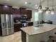 Well-lit kitchen with stainless steel appliances, dark cabinets, and a granite island that includes a stainless steel sink at 5821 Hevena Ct, Palmetto, FL 34221